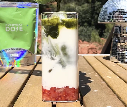 Glass with a layered drink on a wooden table next to a 'Everyday Dose' package.