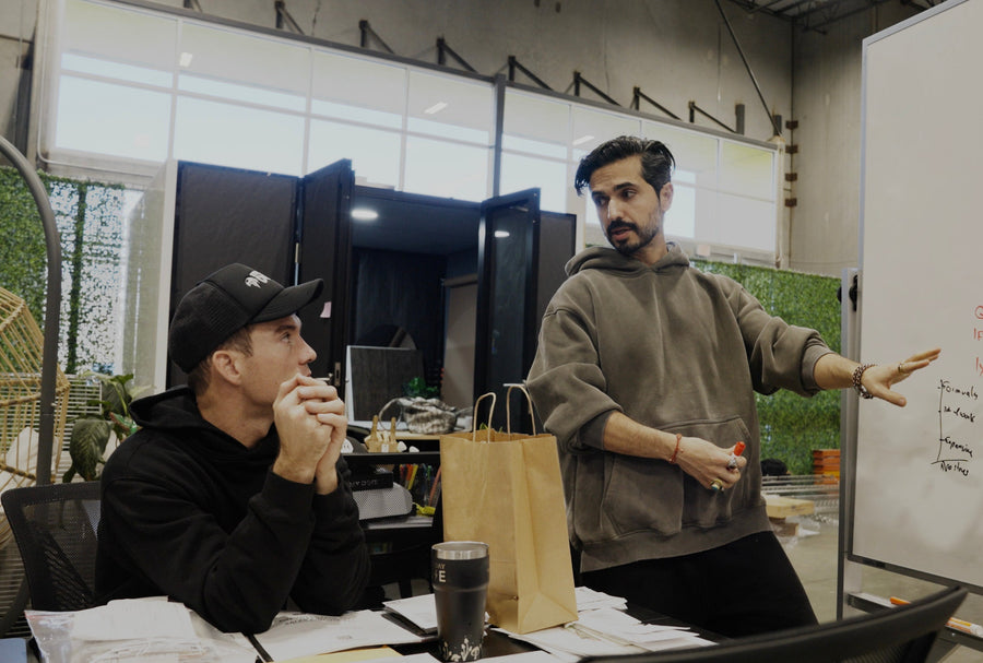 Two men in a meeting room with one pointing at a whiteboard.